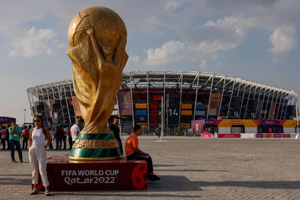 People pose for photos next to a giant replica on the World Cup trophy in front of Stadium 974 on November 18, 2022 in Doha, Qatar