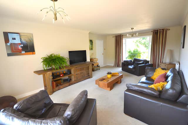 Floor-to-ceiling windows and garden-facing sliding doors give the spacious sitting room a strong connection with the outdoors