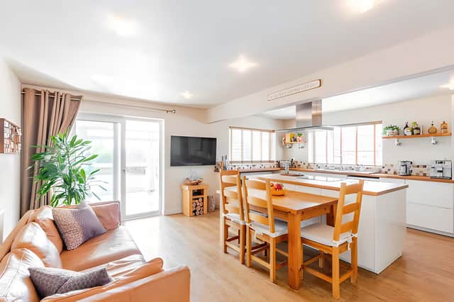An impressive open-plan kitchen, dining and living area brings together a breakfast bar and central island for family life