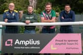 Representatives of Amplius and Ampthill Town Football Club post in front of the new Amplius sponsorship board at the club's home stadium.