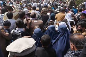 Afghans gather on a roadside near the military part of the airport in Kabul hoping to flee from the country after the Taliban's military takeover of Afghanistan