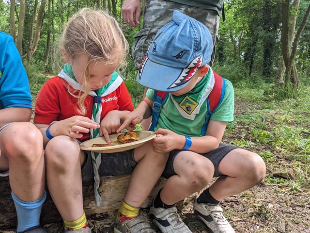 Two Squirrel Scouts share food on a plate