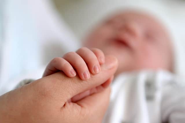 A new born baby grasps her mother's thumb