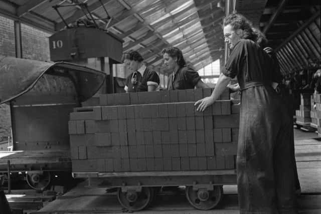 Woman war workers loading bricks onto a train at the London Brick Company factory in Bedford during World War II, August 1941.