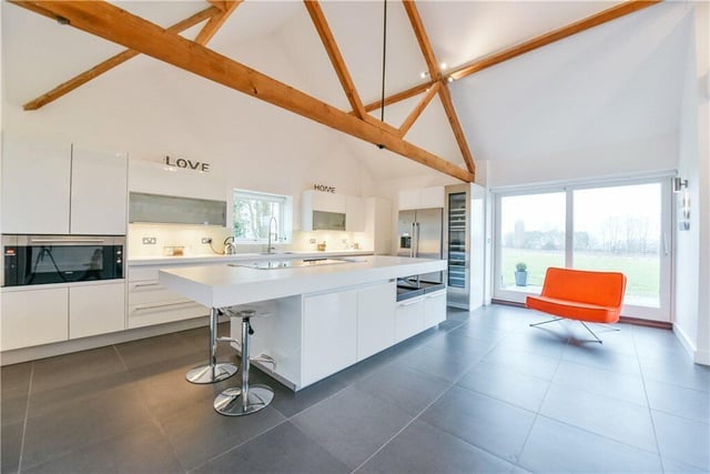 The kitchen/breakfast room has a range of contemporary Poggenpohl white high gloss units with work surfaces incorporating a sink and Hansgrohe tap. The island includes a breakfast bar. There are also integrated Siemens appliances and a set of sliding doors leads to the terrace