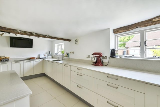 The dual-aspect kitchen/breakfast room has porcelain floor tiling and a range of cream-fronted Shaker style units