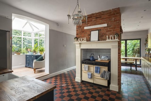 The room features an exposed brick chimney stack centrepiece, with range cooker to one side, log store and dining area to the other