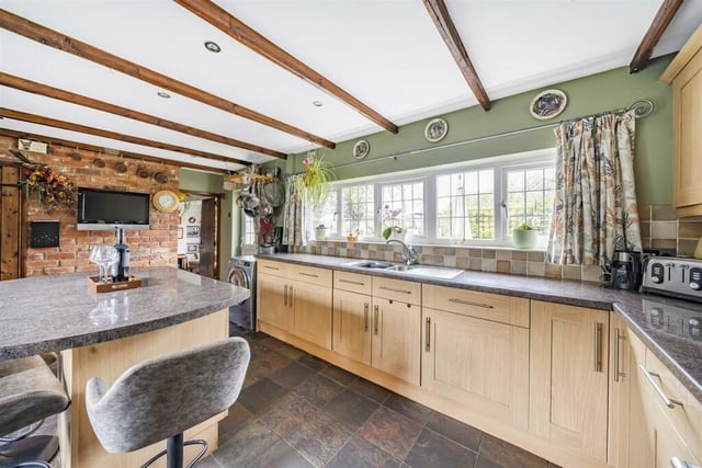 The spacious kitchen boasts a central island and has an attractive exposed brick wall. There is also a door leading to the garden