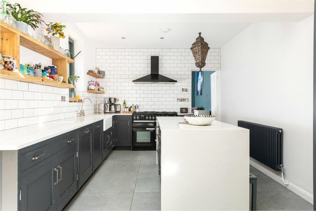 The kitchen has a range of painted Shaker style units, including a larder unit and central island, with quartz worksurfaces and metro tiling. Integrated appliances include a dishwasher, and there is space for a range cooker and American fridge/freezer