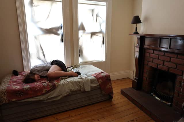 A woman shelters looking scared on a bed (Picture posed by model)