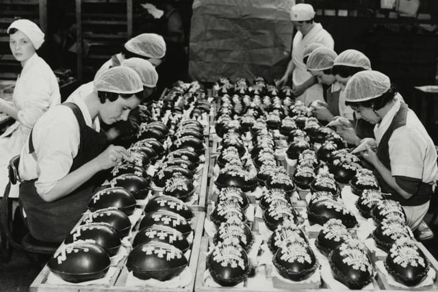 Women at work decorating chocolate Easter eggs at a Bedford confectionery works. The eggs are filled with berries and have a Coronation design, Bedford.