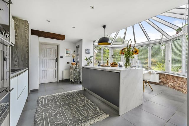 The kitchen, which in turn opens out to a conservatory area providing dining space, includes Minerva worksurfaces and a waterfall Minerva island