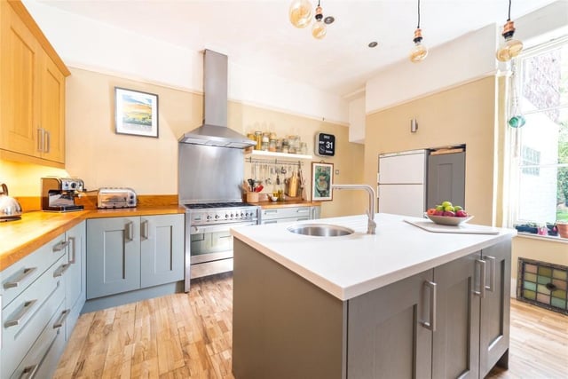 Exposed wood flooring continues through a wide aperture to the kitchen which has a range of oak and hand-painted Shaker-style units with hardwood work surfaces. A central island has Corian worksurfaces and an inset sink and drainer