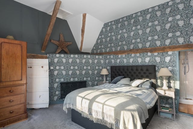 Featuring distinctive William Morris wallpaper, this bedroom also boasts a wardrobe in the eaves as well as an en suite
