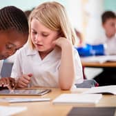 Two school pupils wearing uniform using digital tablet