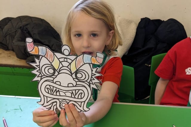 A Squirrel Scout showing a coloured in dragon mask