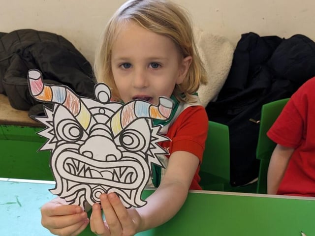 A Squirrel Scout showing a coloured in dragon mask