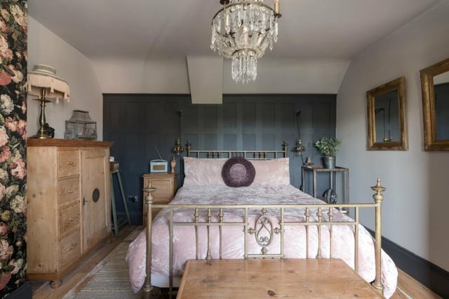 This main bedroom has a sloping ceiling, panelled and muralled walls as well as a reclaimed Victorian fireplace
