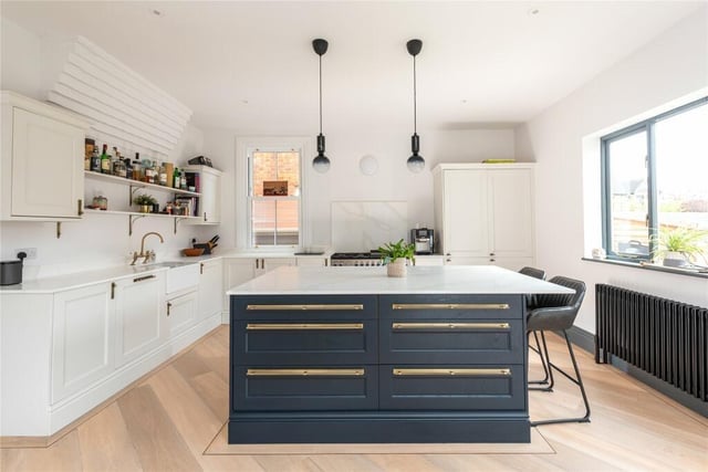 The kitchen features a central island unit incorporating a breakfast bar. The quartz work surfaces incorporate a Belfast sink and a range style cooker