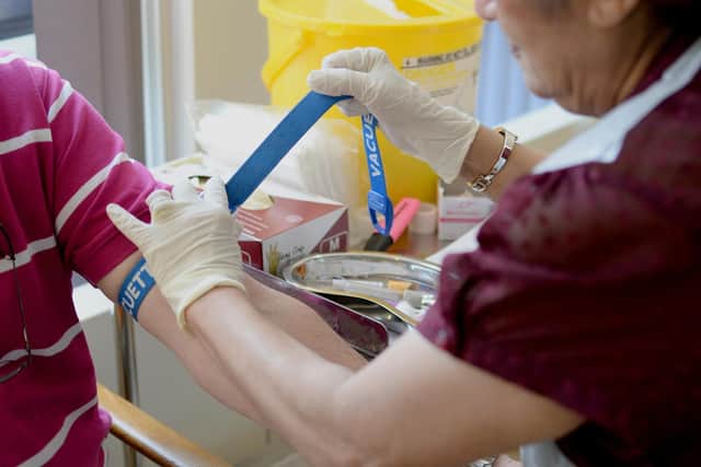 A nurse ties a tourniquet before taking blood