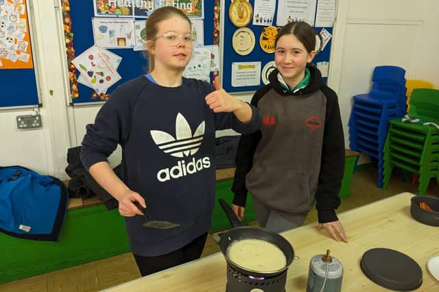 Two Scouts cooking a pancake on a camping stove.