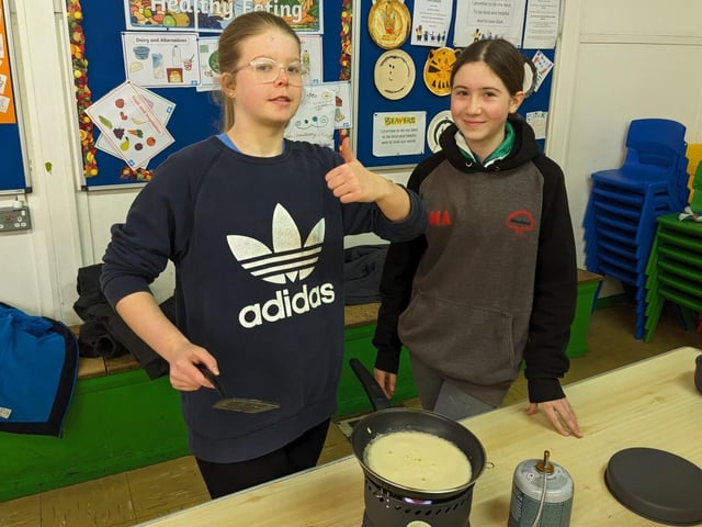 Two Scouts cooking a pancake on a camping stove.