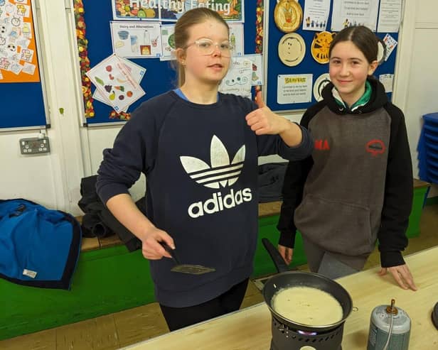 Two Scouts cooking a pancake on a camping stove.