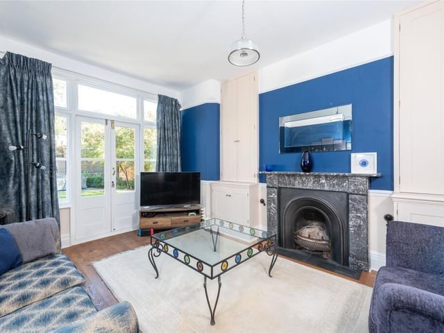 The snug has a marble fireplace and custom-built cupboards, as well as glazed double doors with wing windows to the outdoor seating area in the garden