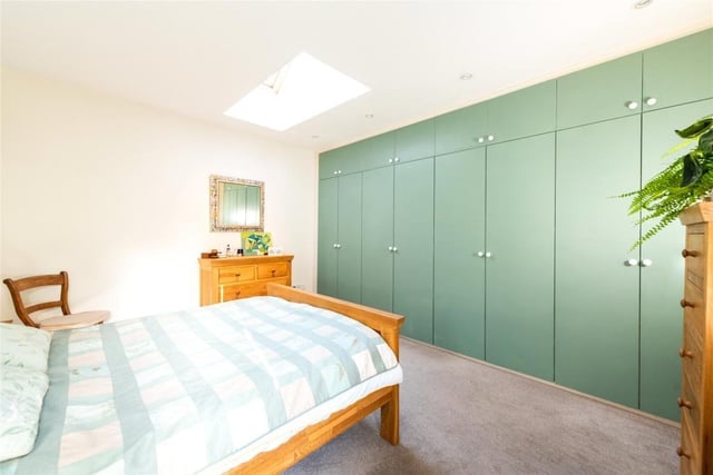 This principal bedroom - which measures 14ft 2in by 13ft 3in - has fitted wardrobes spanning one wall