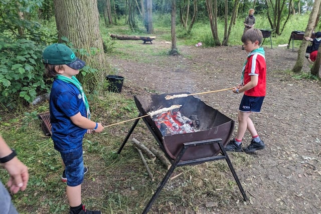 Cub Scouts cooking bread twists over a campfire