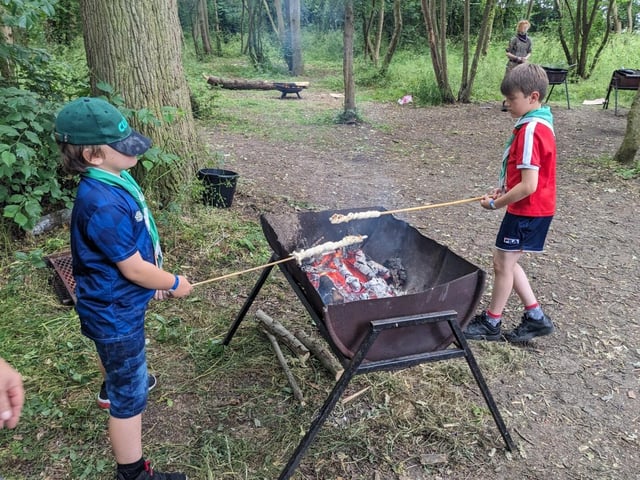 Cub Scouts cooking bread twists over a campfire