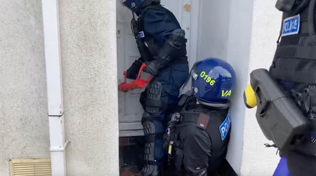 Officers gain entry to a house during a raid