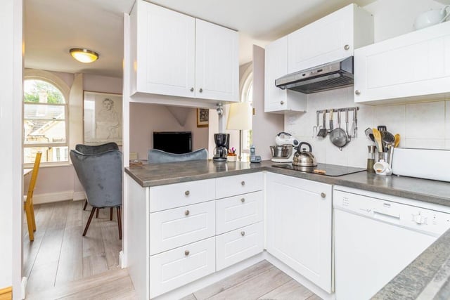 The kitchen is fitted with a matching range of base and eye level units with worktop space over, stainless steel sink unit with single drainer and mixer tap. There's an electric hob, a space for a dishwasher. And the room features an arched sash window to the front and side aspect
