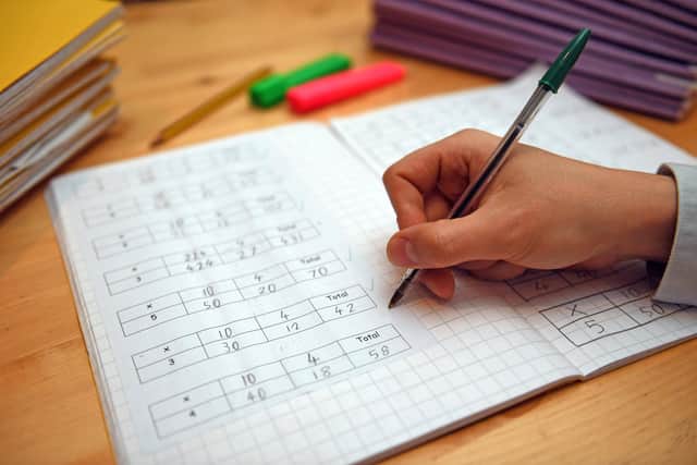 A primary school teacher marking a pupil's maths homework