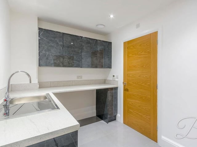 Here is that utility room, which has its own sink, work surfaces and storage units. There's space for a washing machine too.
