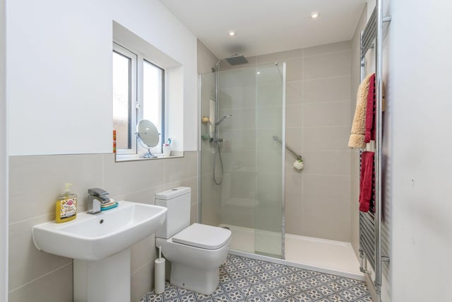 This room is sizable. Neatly presented, there’s neutral tiling to the walls, pretty patterned tiling to the floor, and chrome fixtures and fittings. The owners replaced the bath with an oversized walk-in shower with a rainhead