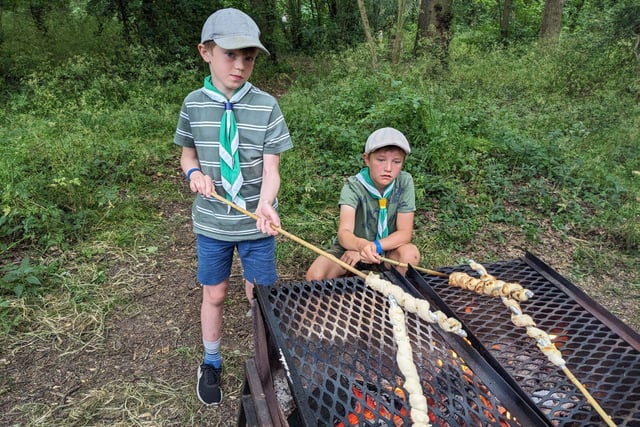 Cub Scouts cooking bread twists over a campfire