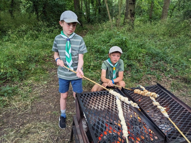 Cub Scouts cooking bread twists over a campfire
