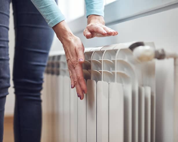 Woman heating her hands on the radiator during cold winter days.