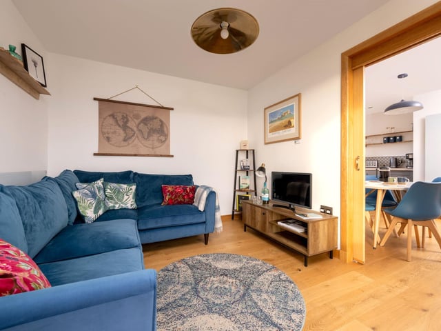 The living room includes a television and a butter-soft corner sofa.
