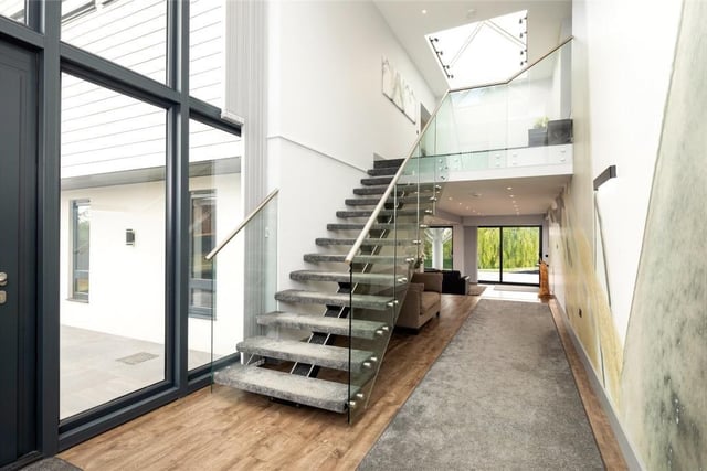 Entering the property via the main door with side and double height glazed panelled windows, the reception hall is an impressive size with open tread and illuminated staircase on to the first floor which has glass partitions and steel handrails