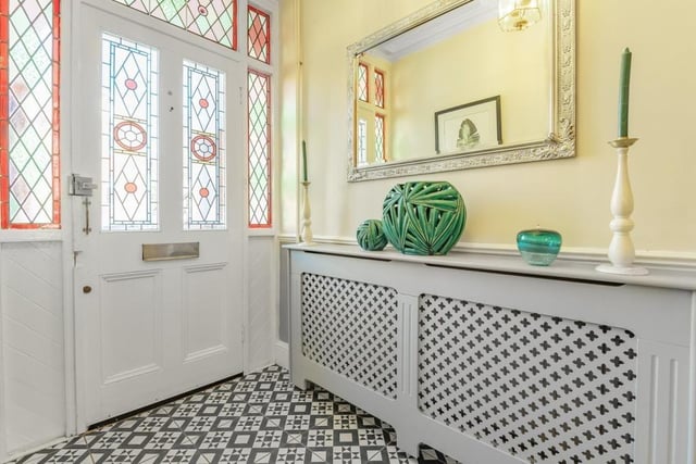 The entrance door with original stained glass panels leads you into the spacious tiled hallway with stairs to first floor