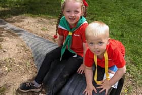 Two Squirrel Scouts sit on a plastic tunnel