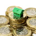 Close up of a minature house resting on new pound coins with a white background