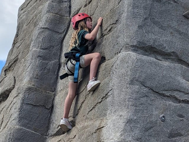 A Cub Scout climbs and outdoor climbing wall