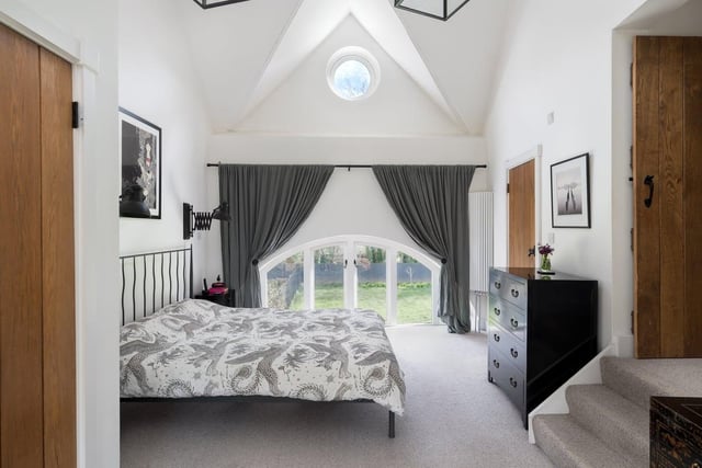 Just gorgeous, this bedroom boasts a vaulted ceiling, semi-circular views of both the church spire and the front garden, and a porthole window to the stars