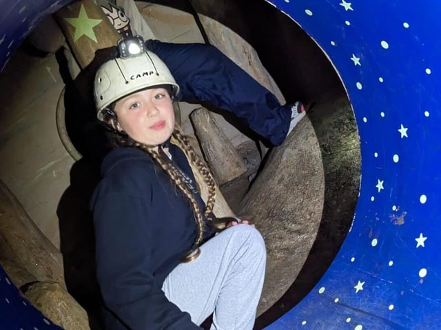 A Cub Scout crouches inside a plastic tunnel