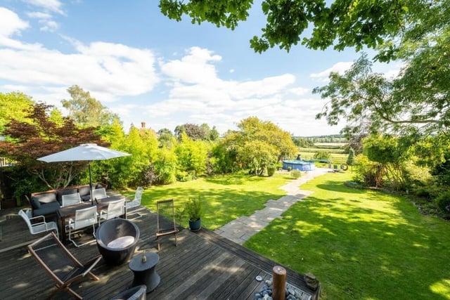 The wraparound deck accessible from the open-plan area is perfect for outdoor relaxation, with an Acer tree and a contemporary water feature. The manicured lawn extends to the rear boundary, where a central patio provides additional seating