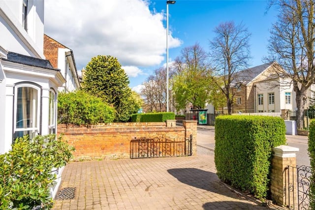 The front garden is bound by an ornate wall with mature hedgerow set behind an iron postman's gate. A gated block paved driveway provides parking for three cars
