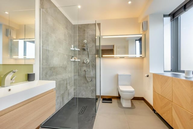 Fitted with a contemporary suite including a floating vanity unit and a large shower cubicle with Hansgrohe wall mounted shower mixer with shower head